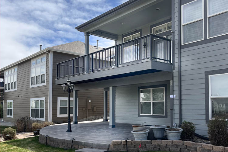 Trex deck with aluminum railing, steel-framing and grey stamped concrete patio underneath the elevated deck
