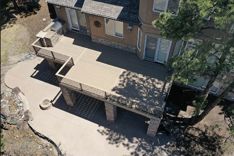 Trex Deck with aluminum Black-metal Railing, steel-framing, stone columns and stamped concrete patio - drone shot